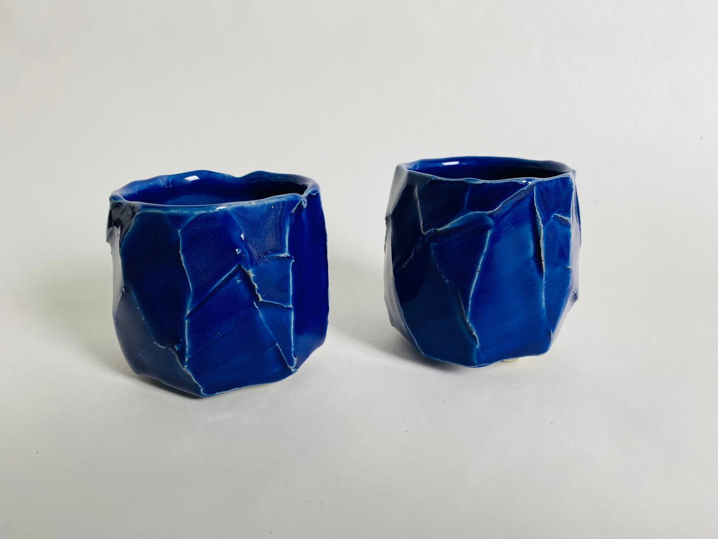 A pair of small faceted blue cups