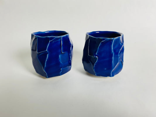 A pair of faceted blue cups