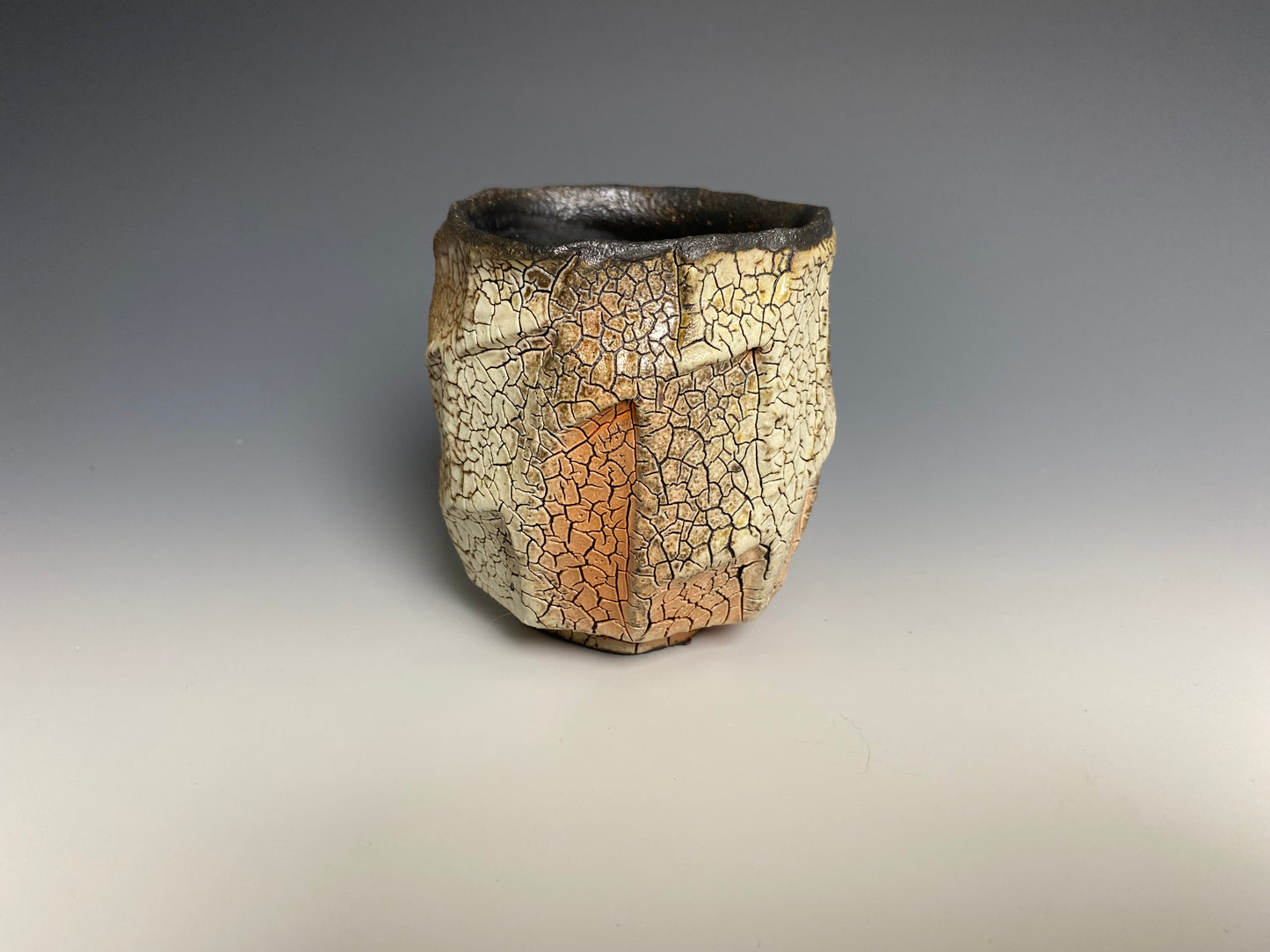 Wood fired faceted yunomi with crackle slip, black clay.