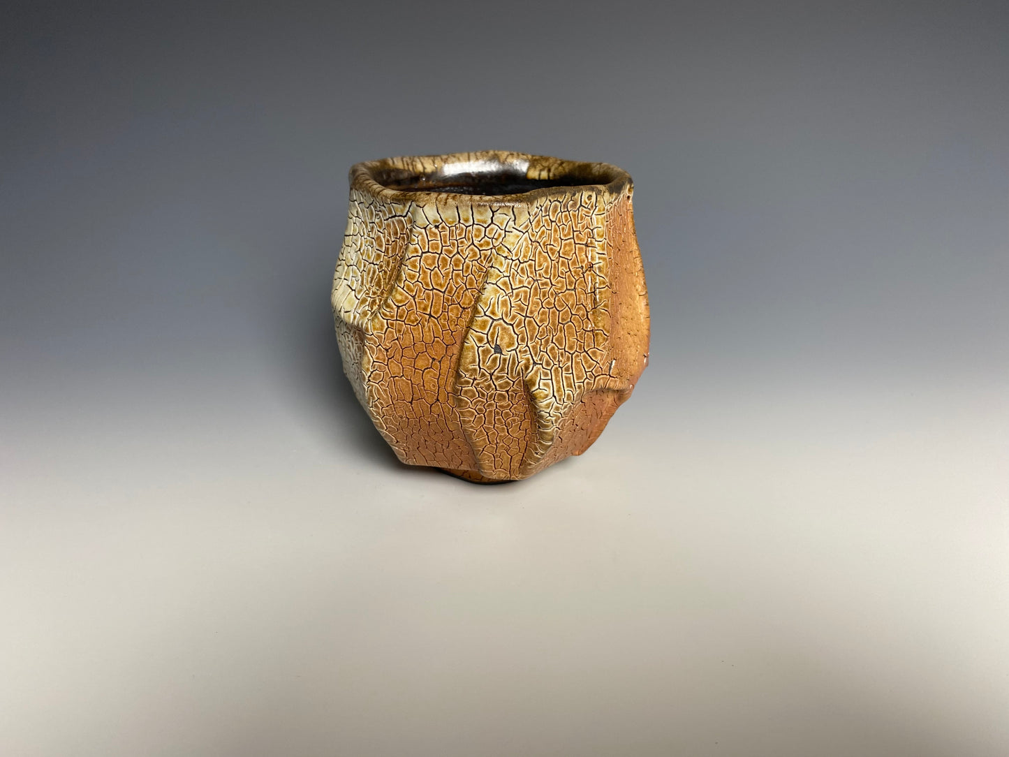 Wood fired faceted yunomi with crackle slip, black clay.