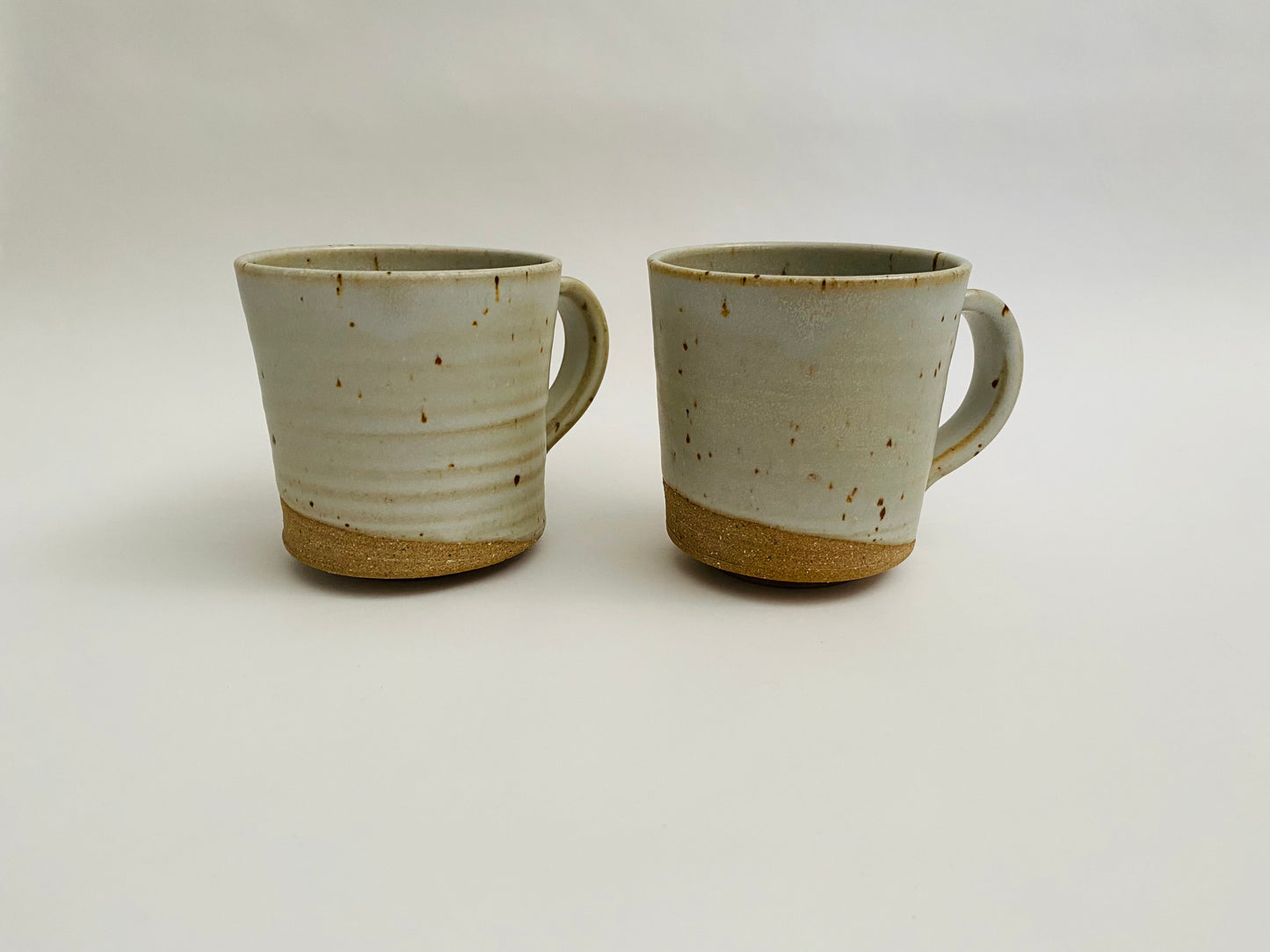 A pair of stoneware mugs in a matte glaze