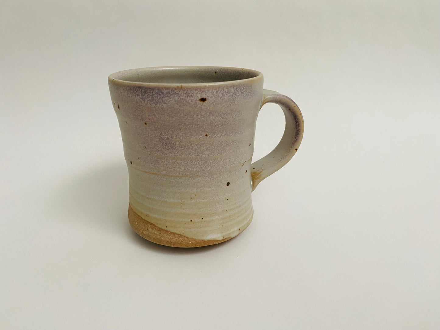 Stoneware mug, matte glaze with lavender blushing, bare clay accent.